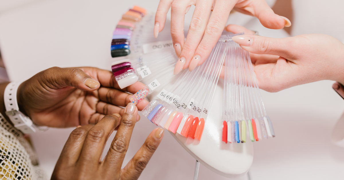 Twee handen en een kleuren waaier met diverse kleuren voor nagels.